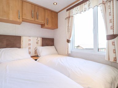 A bedroom with two single beds a window with curtains and overhead cabinets at Whiteside in Lorton