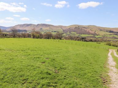 A grassy field with a dirt path and hills in the background at Whiteside in Lorton