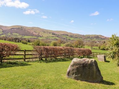 A grassy yard with two large stones a wooden fence and hills in the background at Whiteside in Lorton