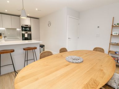 A kitchen and dining area with wooden table chairs bar stools and shelving at Sebastian's View in Falmouth
