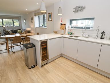 A kitchen with white cabinets a sink and drying rack next to a dining table with chairs and a sofa in the background at Sebastian's View in Falmouth