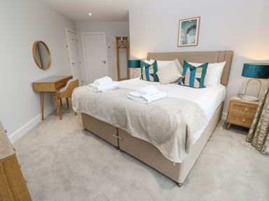 A bedroom with a bed towels and pillows a desk with a chair and a round mirror at Sebastians View in Falmouth