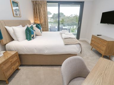 A bedroom with a bed pillows side tables a chair desk dresser and a wall mounted TV at Sebastian's View in Falmouth