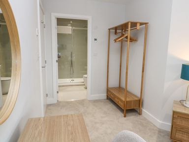 A bedroom with a wooden clothes rack hangers and a bathroom visible through an open door at Sebastians View in Falmouth