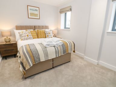 A bedroom with a bed with patterned pillows and blanket two bedside tables with lamps and a framed picture on the wall at Sebastians View in Falmouth