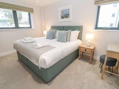 A bedroom with a double bed side table lamps and a desk at Sebastians View in Falmouth
