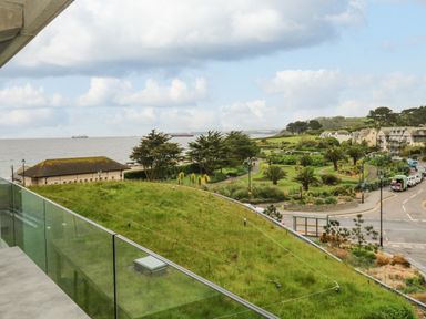 A coastal view from a balcony overlooking a grassy roof garden park road and houses near the sea at Sebastians View in Falmouth