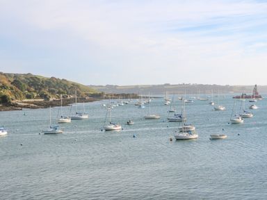 A bay with many sailboats anchored near a coast with hills at Sebastians View in Falmouth