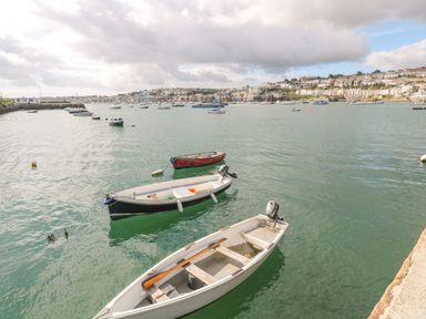 A harbor with several small boats floating on water and a town on the hillside in the background at Sebastian's View in Falmouth