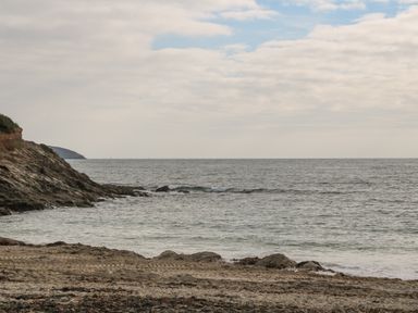 A rocky beach with waves and a partly cloudy sky at Sebastian's View in Falmouth