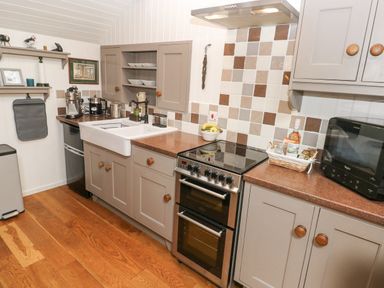A kitchen with a stove oven sink cabinets and countertop appliances at Coach House in Haverfordwest near Broad Haven