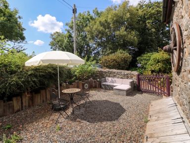 A garden with a table and chairs under an umbrella at Coach House Haverfordwest near Broad Haven