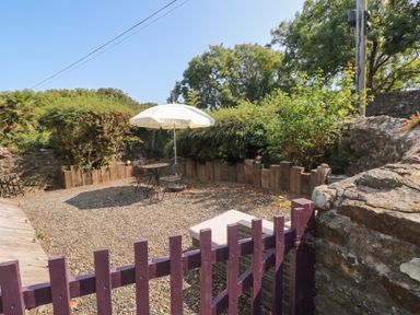 A garden with a table and chairs under an umbrella at Coach House Haverfordwest near Broad Haven