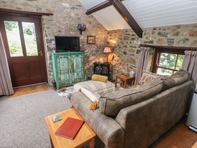 A living room with a sofa and television at Coach House in Haverfordwest near Broad Haven