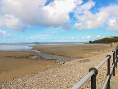 A beach with a stream and rocks at Coach House Haverfordwest near Broad Haven