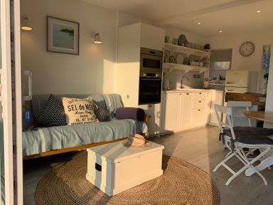 A kitchen and sitting area with sofa cushions coffee table and dining chairs at Little Beach in Seaview