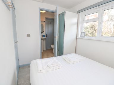 A bedroom with a bed with folded towels a window a closet and an open door leading to a bathroom at Little Beach in Seaview