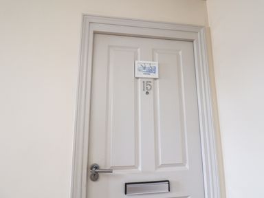 A closed white door with number 15 and a small sign with birds above the number at Kittiwakes The Bay - Filey