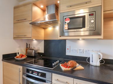 A kitchen countertop with a microwave oven toaster electric kettle cutting board bread and tomatoes at Kittiwakes The Bay Filey