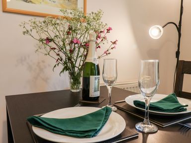 A dining table with two place settings green napkins wine bottle and flowers at Kittiwakes The Bay - Filey