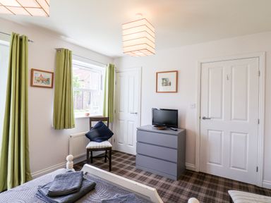 A bedroom with a bed folded towels a chair with cushions a dresser and a small TV at Kittiwakes The Bay Filey