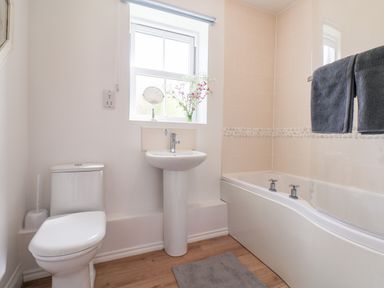 A bathroom with a toilet sink and bathtub with towels hanging at Kittiwakes The Bay Filey
