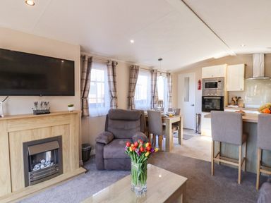 An open living room and kitchen area with a brown recliner chair and dining table at Marigold Lodge in Runswick Bay near Staithes