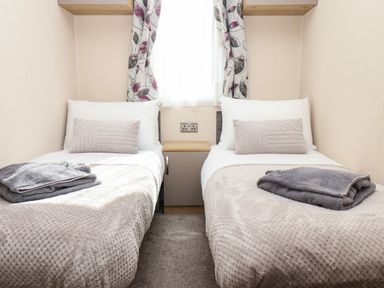 A bedroom with two single beds and a cabinet between them at Marigold Lodge in Runswick Bay near Staithes