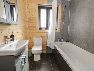 A bathroom with a sink cabinet toilet and bathtub at Sunset Lodge 5 in Llanbedr