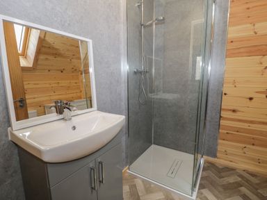 A bathroom with a sink and cabinet and a glass shower enclosure at Sunset Lodge 5 in Llanbedr