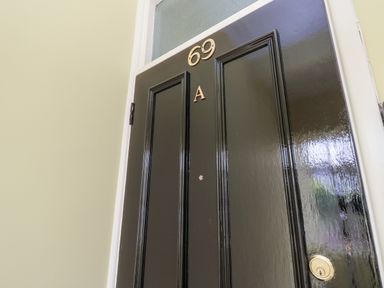 A black door with the numbers 69 and letter A on it at Chine Heights in Bournemouth