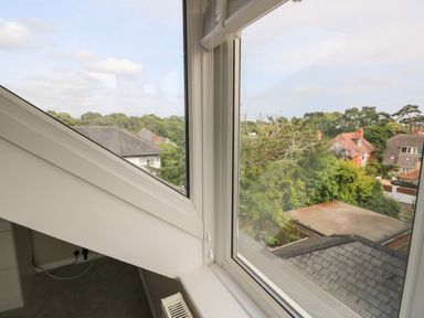 A corner window with a view of rooftops trees and houses at Chine Heights in Bournemouth