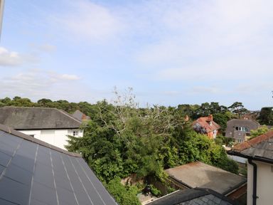 View of rooftops trees and houses under a cloudy sky at Chine Heights in Bournemouth