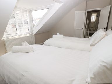 A bedroom with two beds with white bedding and towels on top at Chine Heights in Bournemouth