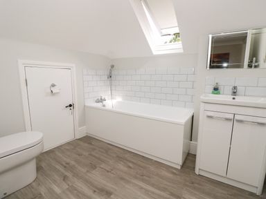 A bathroom with a bathtub shower toilet and sink cabinet at Chine Heights in Bournemouth