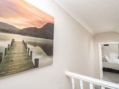 A hallway with a landscape picture on the wall and a view into a bedroom at Chine Heights in Bournemouth