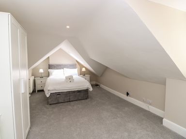 A bedroom with a double bed between two bedside tables and a wardrobe in an attic at Chine Heights in Bournemouth