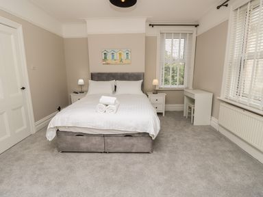 A bedroom with a double bed white linens bedside tables lamps and a small desk at Chine Heights in Bournemouth