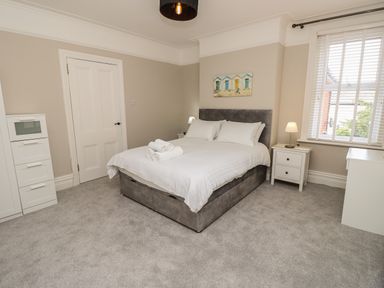 A bedroom with a double bed a nightstand with a lamp a window with blinds and a white door at Chine Heights in Bournemouth