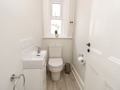 A small bathroom with a toilet sink and a window with a plant at Chine Heights in Bournemouth