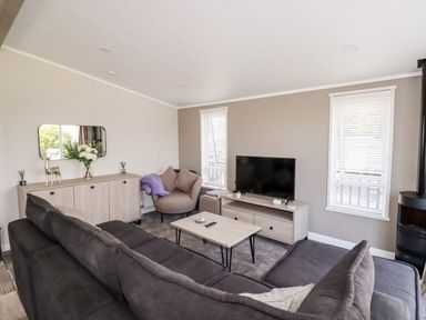 A living room with gray sofas a coffee table and a TV on a stand at 63 The Maples in Hewas Water near Sticker