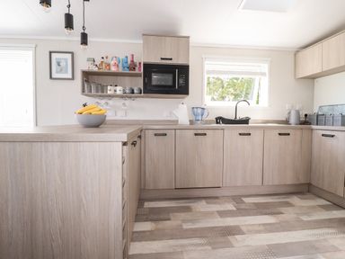 A kitchen with wood cabinets a microwave bananas on the counter and a window at 63 The Maples in Hewas Water near Sticker