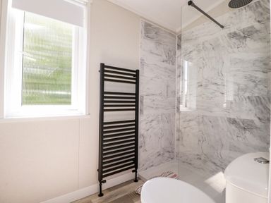 A bathroom with a window black towel radiator shower area with marble walls and a toilet at 63 The Maples Hewas Water near Sticker