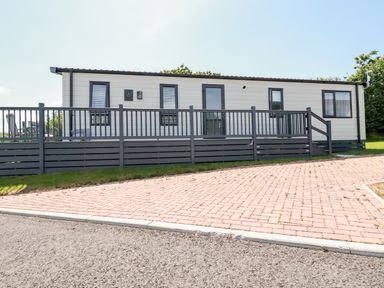 An exterior view of a mobile home with a raised deck and railing at 63 The Maples in Hewas Water near Sticker