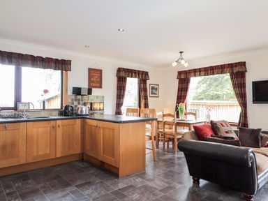 A kitchen and dining area with wooden cabinets dining table and sofa at Lovat Highland Bothy in Beauly