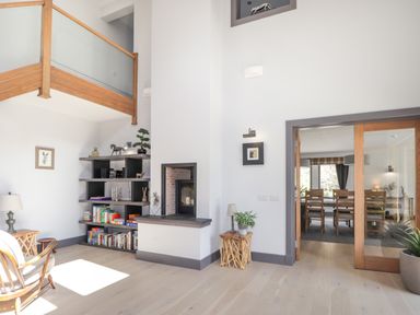 A living room with wooden chair bookshelf and a fireplace next to a dining room with wooden chairs at Ben Luna Lodge Drumnadrochit Loch Ness