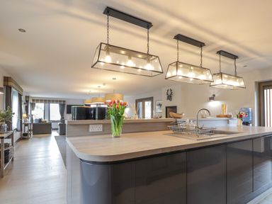 A kitchen with a wooden countertop and hanging lights overlooking a living area at Ben Luna Lodge in Drumnadrochit Loch Ness