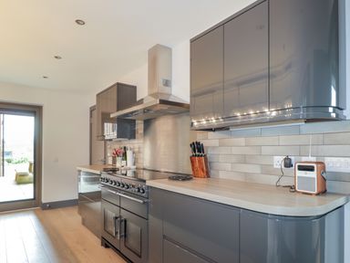 A kitchen with grey cabinets a stove a knife block and a small radio at Ben Luna Lodge in Drumnadrochit Loch Ness