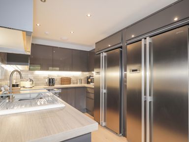 A modern kitchen with stainless steel refrigerators gray cabinets and a sink with a drying rack at Ben Luna Lodge in Drumnadrochit Loch Ness