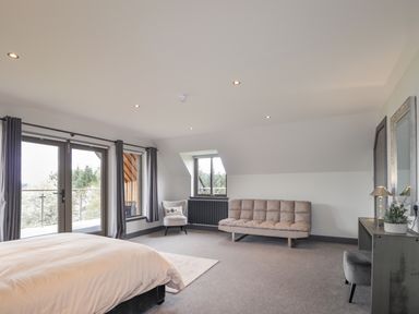 A bedroom with a bed a chair a sofa a desk and a door leading to a balcony at Ben Luna Lodge in Drumnadrochit Loch Ness